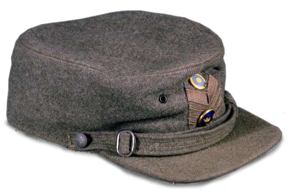 Uniform av diagonalvävt ylletyg. Guldgaloner och gradbeteckningar av gulmetall. Knappar av gulmetall med riksäpple. Fodrad med grått konstsiden. Skärp av brunt läder med axelrem. Skärp av metalltråd i guld och blått, läderfodrat, mässingsspänne. Uniformsmössa av grått kypertvävt ylle. Svart läderskärm, guldsnodd. Mässingsknapp och emaljkokard. Text: Arméns centrala beklädnadsverkstad. Skärmmössa med skärm av tyget. Båtmössa.