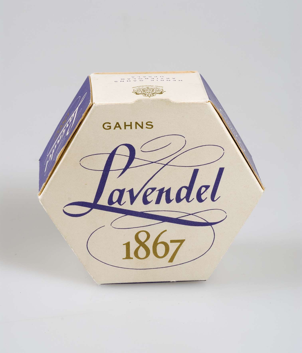 Förpackning med tvål, vit med text i lila och guld "Gahns Lavendel 1867. Henrik Gahns Aktiebolag Uppsala". Innehåller en gulvit rund tvål.