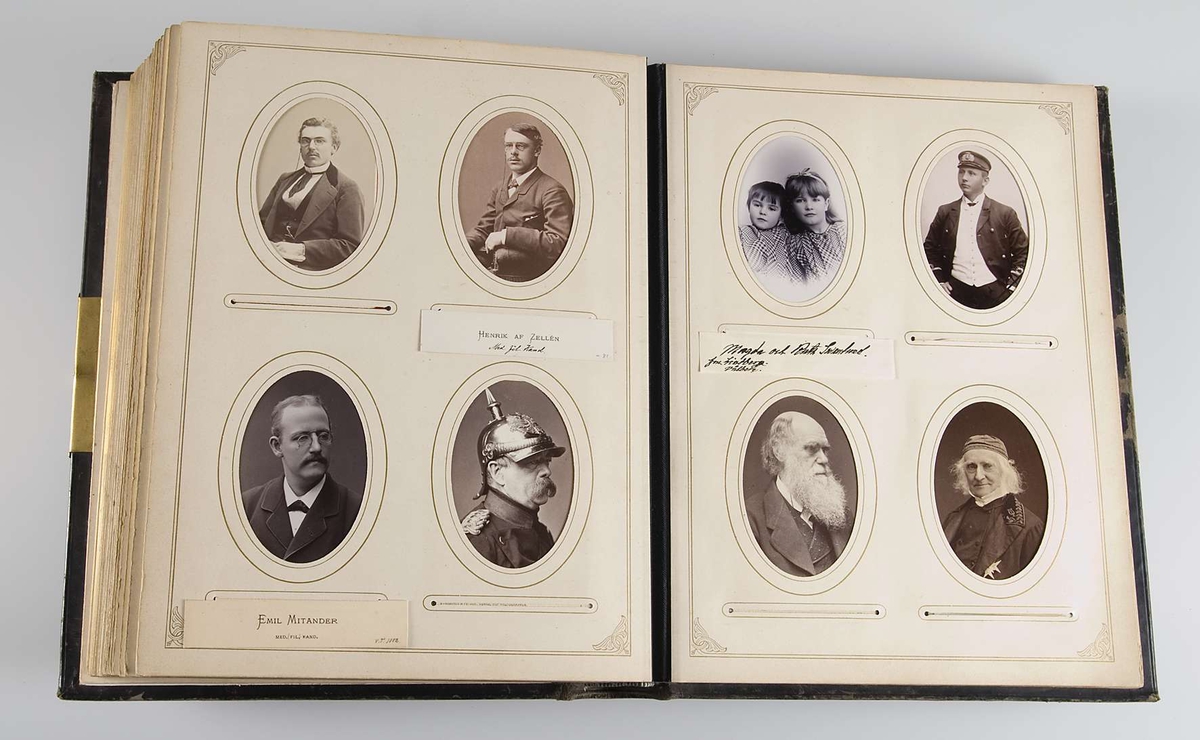 Fotoalbum med pärmar av svart läder och dekor i relief och guldtryck. På framsidans pärm finns en mittspegel av glas på vilket ett landskapsmotiv i månsken är målat. På baksidans pärm finns fyra nitar av metall.