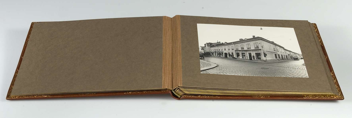 Album, inbundet i helfranskt band i brunt läder med stämplade ramverk och ornament i guld. På pärmens framsida spegelmonogram, komponerat av bokstäverna GEK (Gustaf E. Karlsson). Guldsnitt runt om, blad av mörkgrå kartong. Frontespis med textad tillägnan: "Till Direktör Gustaf  E. Karlsson 60-årsdagen 19 30/10 28. Med varm lyckönskan och tack för värdefullt arbete. Uppsala Specerihandlarförening". Albumet innehåller fotografier av Gustaf E. Karlsson, av hans speceriaffär, av styrelsen i Uppsala Specerihandlarförening samt av föreningens hedersledamöter och medlemmar. Albumet på pärmens baksida stämplat: "Levins Bokbinderi. Uppsala Bokband C W Bergman". Mapp, klädd med mörkbrunt läder. 