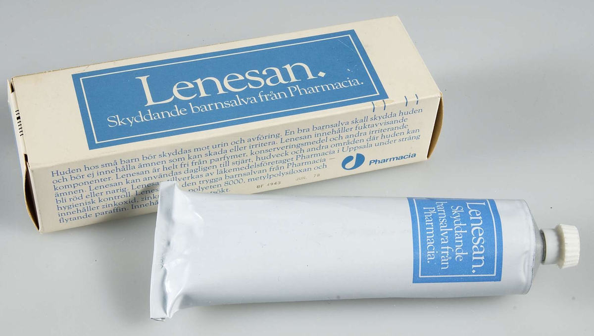 Ask av vitt papper med text i ljusblått och vitt "Lenesan. Skyddande barnsalva från  Pharmacia". I asken vit och ljusblå tub med samma text.
