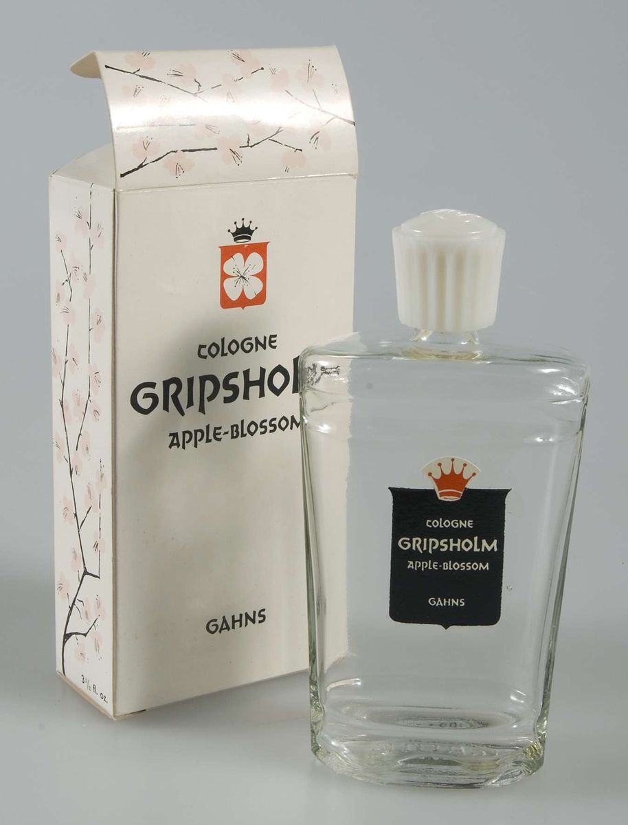 Oöppnad förpackning. Flaska av ofärgat glas med skruvlock av vit konstmassa, refflad, med tillverkarnamnet i relief. Liten etikett av svart papper med text: COLOGNE GRIPSHOLM APPLE BLOSSOM. I förpackning av vit papp med tryckt dekor på kortsidan och på locket i form av rosa äppelblom, och text i svart som ovan.