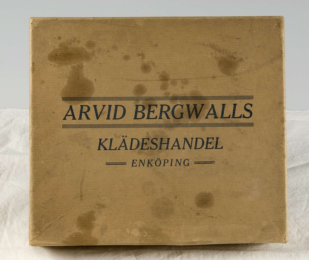 Nio häften med typgrover i kartong av brun papp. Kartongen märkt med blått tryck: ARVID BERGWALLS KLÄDESHANDEL, ENKÖPING. Alla häften märkta med tryck: ARVID BERGWALL, ENKÖPING. Åtta häften har omslag av vävimiterande papp, tre i brun färg och fem i grön färg. Ett häfte med omslag av papp i orangegul färg. Alla häften innehåller tygprover uppklistrade på pappark. Under tygproverna finns en svart ram och svart tryck med artikelnummer, tygbredd, pris och typ av tyg.
Häfte 1, svart tryck: STAPELVAROR i Skotska kostymtyger.
Häfte 2, svart tryck: NYHETER för Vår- & Sommarsäsongen 1928, Kostymtyger, Häftet 3.
Häfte 3, svart tryck: NYHETER för Vår- & Sommarsäsongen 1941, Klänningstyger, Bomullstyger och Fodervaror, Häftet 4.
Häfte 4, svart tryck: NYHETER för Vår- & Sommarsäsongen 1940. Bomullstyger och Fodervaror, Häftet 6.
Häfte 5: NYHETER för Höst- och Vintersäsongen 1941 - 42, Herrvaror, Häftet 1.
Häfte 6: NYHETER för Höst- och Vintersäsongen 1941 - 42, Skinnimitationer och Skidmilton, Häftet 2.
Häfte 7: NYHETER för Höst- och Vintersäsongen 1941 - 42, KAPPTYGER, Häftet 3.
Häfte 8: NYHETER för Höst- och Vintersäsongen 1941 - 42, Klänningstyger, Häftet 4.
Häfte 9: NYHETER för Höst- och Vintersäsongen 1941 - 42, Klänningstyger, Bomullstyger och Fodervaror, Häftet 5.