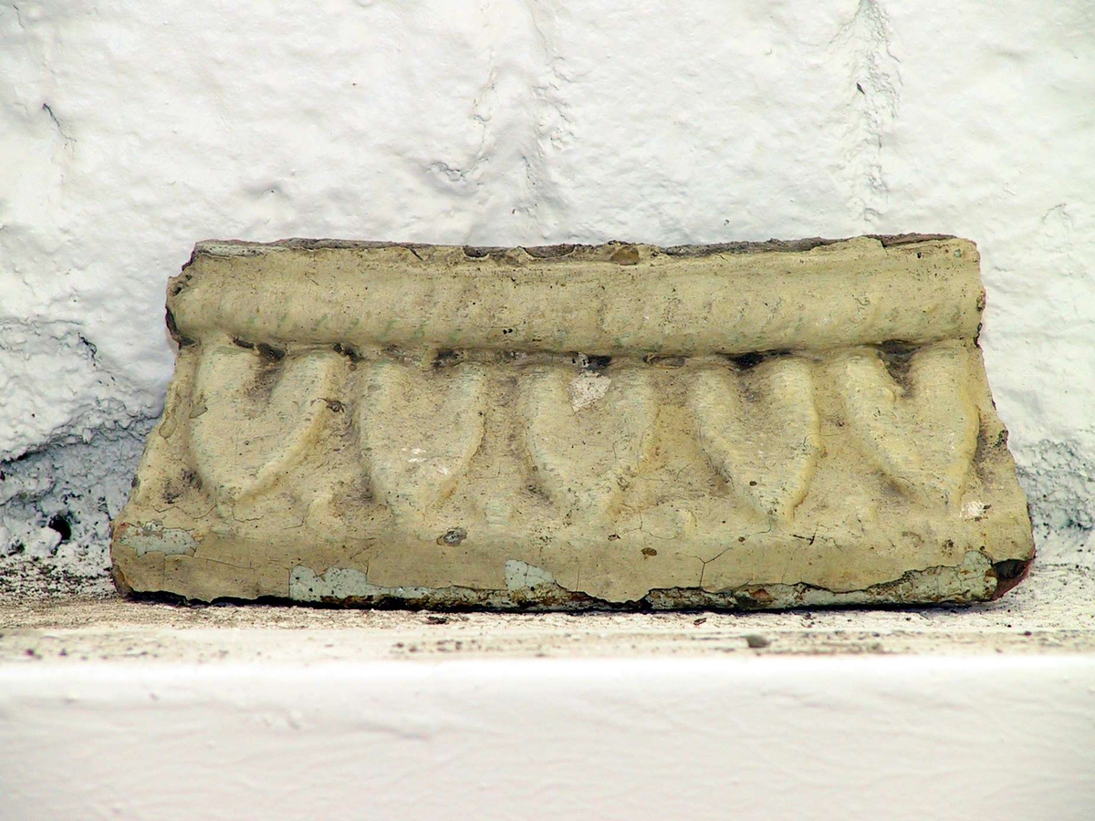 Kakel till rund kakelugn, målade med svagt gul och turkos färg. 45 hela kakel, 35 delar av kakel samt 26 delar till över- och/eller undersims. Vissa av kaklen har märkts med etikett med blå tunn ram.