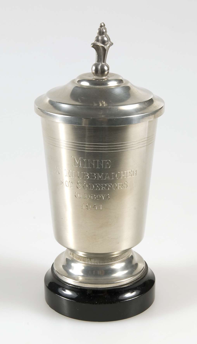 Idrottspris av metall i form av en pokal med lock på underlag av svartmålat trä. På pokalen inskriptionen: MINNE AV KLUBBMATCHEN MOT SÖDERFORS, ODLBOYS 1941.