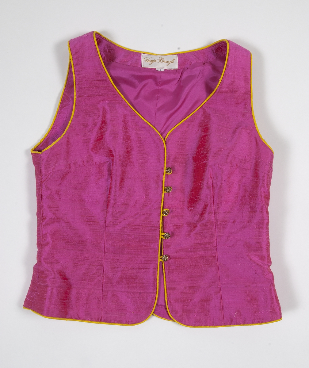 Ärmlöst liv i rosa siden. Livet är formsytt och kantat i gult siden. Livet knäpps på framsidan med agraffknäppning med fem guldfärgade plastknappar som har formen av rosor. Dessa är knäppta med agraffknäppning med öglor i gult siden.Livet är fodrat med rosa fodertyg.