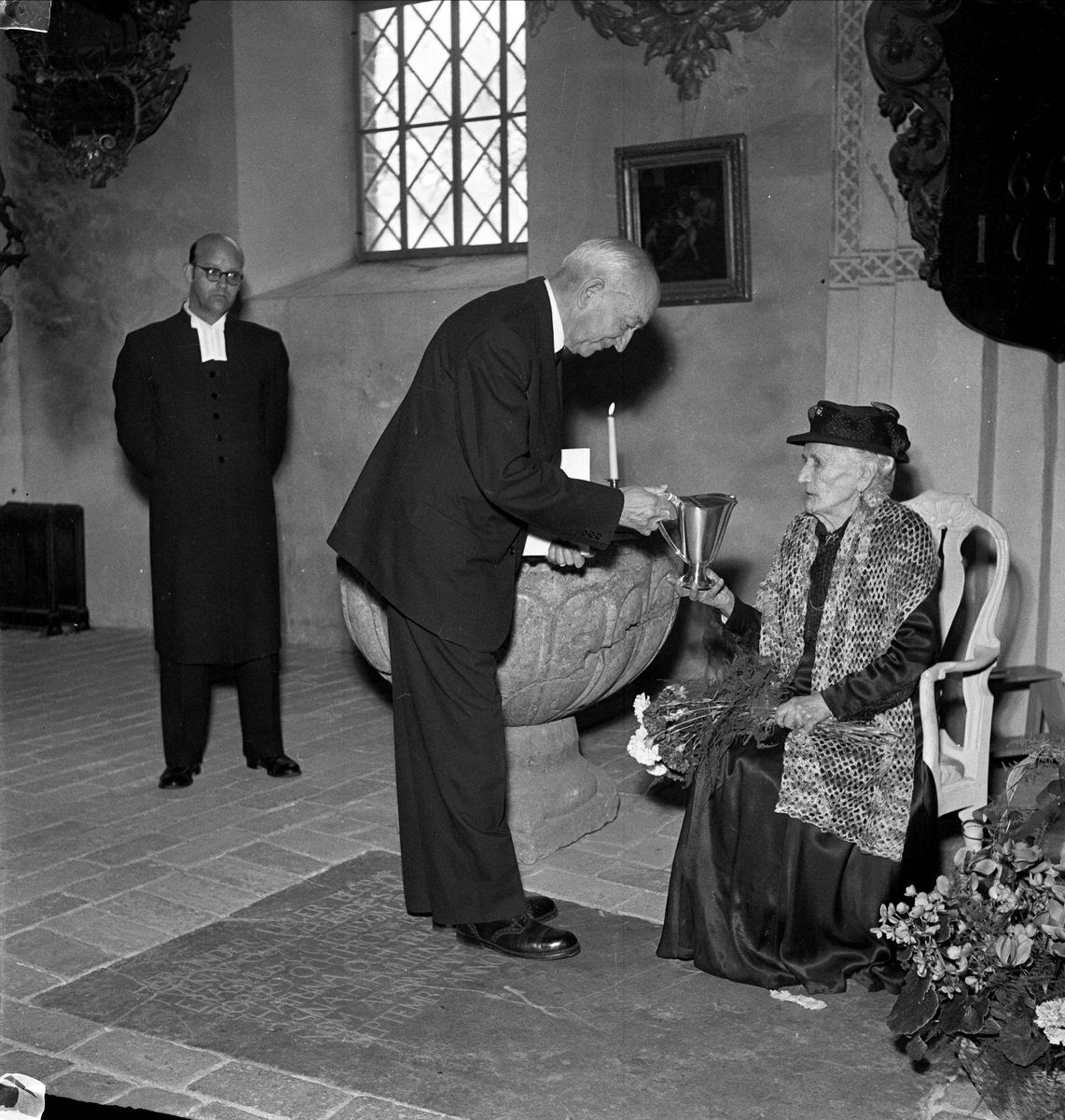 Dop - 100-årig kvinna bär fram sonsonson i Håtuna kyrka, Håtuna socken, Uppland 1954