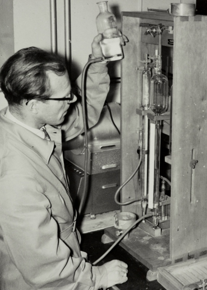 En mann, muligens Lars Brunes, arbeider med en materialundersøkelse i det kjemiske laboratoriet til Jonas Øglænd AS.