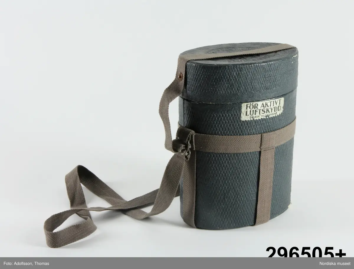 Huvudliggare:
"GASMASK, tyg, metall; förvaras i fodral av hårdpressad papp; se bilaga. Mått fodral Br 19 cm, Tj 12,5 cm, H 25,8 cm.
G från museets skyddsrum, 1939. /1973/ 8/8 Nordiska museet, Stockholm."

Bilaga [kopia av katalogkort]:
"Skyddsmask, storlek 3, i två delar. Ansiktsskydd av kraftigt grått tyg med fastsättningsband av tyg och resår. Skinnskodd kant.
Två syngluggar (diam 8,5 cm) med metallkant och glas. På insidan imskydd av celluloid, fäst med en avtagbar metallfjäder. Imskydden är utbytbara.
Framför näsa och mun ett äggformat metallstycke med två gängade hål. I 'munhålet' sitter ett runt metallstycke (diam 6 cm, h 1 cm) med hål längs ytterkanten. I munstycket sitter ett gummimembran, som ger efter vid utandning. Runt den plana sidans kant står inpressat 'STOCKHOLM BIRGER CARLSON & Co. A.B. 'BICAPA' '. Läderpackning avslutar det gängade partiet. I inandningshålet ligger en gummipackning. Här ska en grå metallbehållare fastskruvas, vilken i sin yttre del är försedd med ett skyddspapper på vilket står: 'Detta papper avlägsnas vid krigsutbrott eller då behållaren ska användas för övning'.  Den gängade delen är skyddad av en kapsyl. På behållaren är stämplat ''1939' B13341E' samt tre kronor. På ena sidan sitter ett blått varu-märke. I fodralet finns också en förpackning stämplat av samme tillv och med årtalet 1939. På förp står 'Imskivor / skyddas för fukt. Får ej avtorkas. Vidröras endast i kanten.' Alltsammans ligger i en grå oval kartong av hårdpressad kartong. På locket är tillverkarens namn inpressat och strax nedanför locket står på ena sidan på en silverfärgad etikett 'FÖR AKTIVT LUFTSKYDD / SVENSK TILLVERKNING'. Runt kartongen (fodralet) sitter tygband, så att skyddsmasken kan bäras över axeln.
1973-08-08 Fynd i Nordiska museet
1976-02-27 BR"