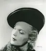 Fb, Porträtt av kvinna i hatt av Elsa Schiaparelli. Den nya silkesflätan saturne, underbrätte av svart sammet.
