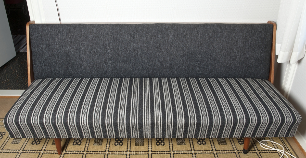 Sofa i teak med svart tekstiltrekk; svart og lysegrått stripemønstret setetrekk. 
