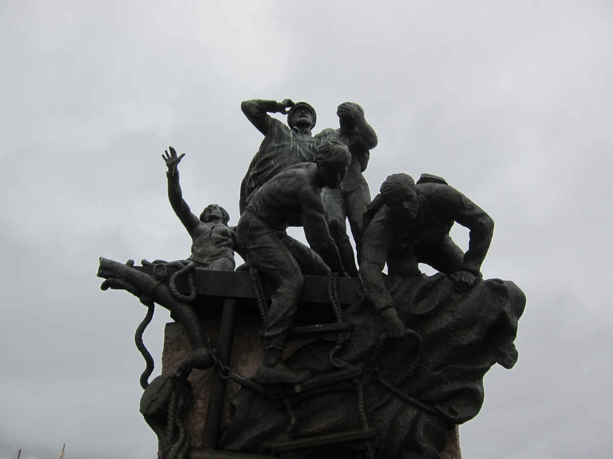 Monumentet forestiller et skipsmannskap på et synkende skip. Monumentet står på en høy stensokkel.