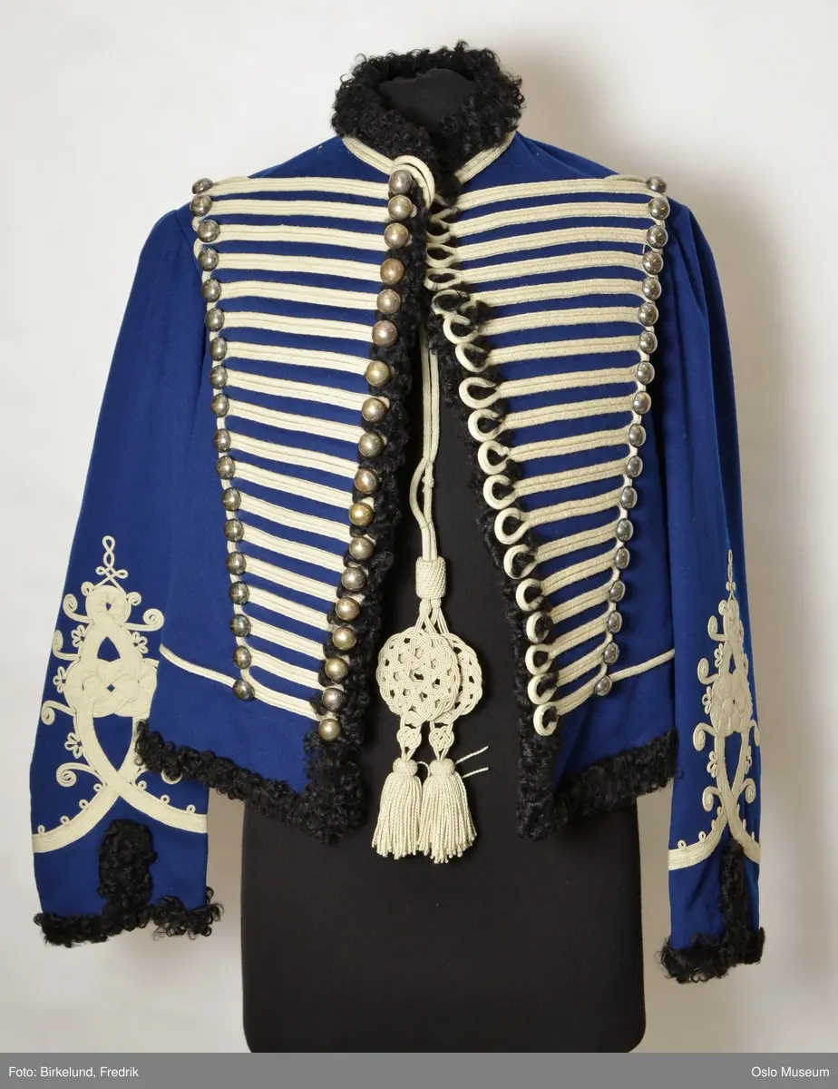 Uniformsjakke. Rød passpoil langs forstykkenes krage. Det gule kor, garden. Uniformslue=D
D: Snor til uniform.