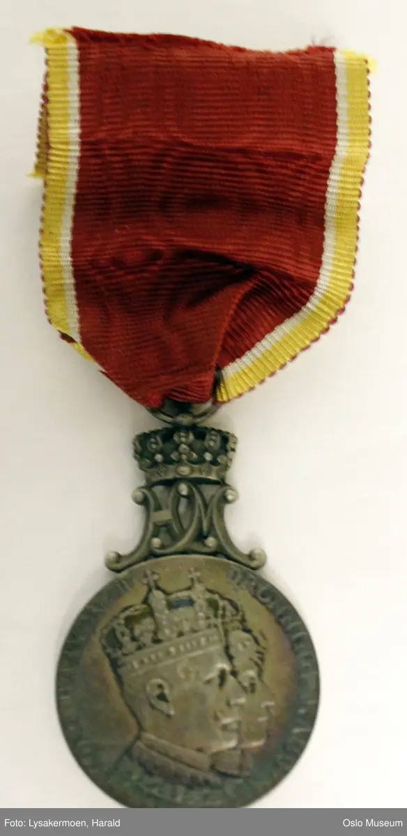 Rund medalje i bånd.

Medaljen er toppet av de sammenflettede bokstavene H og M, disse bærer en kongekrone. Båndet er festet til kronen med en sølvhempe. Båndet er rødt, kantet med hvitt, gull og rødt Medaljen er patinert - gir blåskimrende effekt.

Etuiet er av papp. Det er rødt med en gylden krone på lokket. Foret er hvitt, av silke og bomull. Forsølvet lukkemekanisme. Etuiets mål - L: 10,5 cm. B: 5,7 cm.