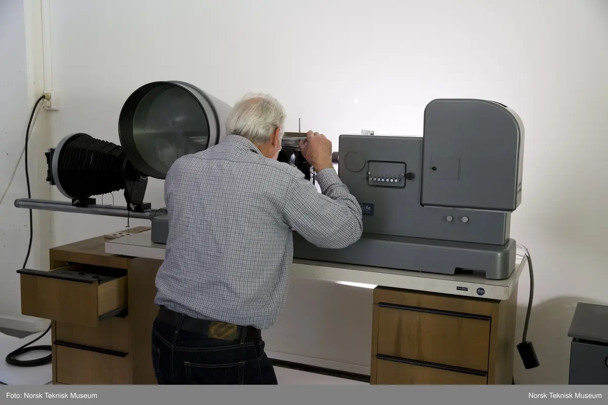 Mikroskopdelen av gjenstanden inkludert belguttrekk for fotografering (inkludert snorutløser), stang til å montere kamerabelg og to tekstilkapper til å legge over gjenstanden
ADVARSEL: Pæra som sitter inne i kabinettet (til høyre på bildet) er en overtrykkspære. Håndteres meget varsomt på grunn av risiko for eksplosjon. Bruk ansiktsskjerm om den håndteres.