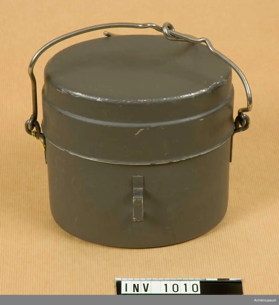Utförd i två delar. Gråmålad. Kärlets undre del utgörs av en oval burk med öglor på sidorna för grepen. På framsidan en låsanordning för locket. 

Locket är gråmålat på utsidan, blankt inuti och försett med ett handtag på framsidan. I denna del kan man steka över eld. För att klara värmen finns på skaftet två ringar i vilka man kan sticka in ett förlängningsskaft av något slag. Skaftet är ledbart i ett gångjärn som också tjänar som lås för locket då detta är påsatt på burken. 

Grepen som bär kärlet är försedd med krok, avsedd att hänga upp burken i över elden eller att kroka fast den i ryggsäcken med under transport.