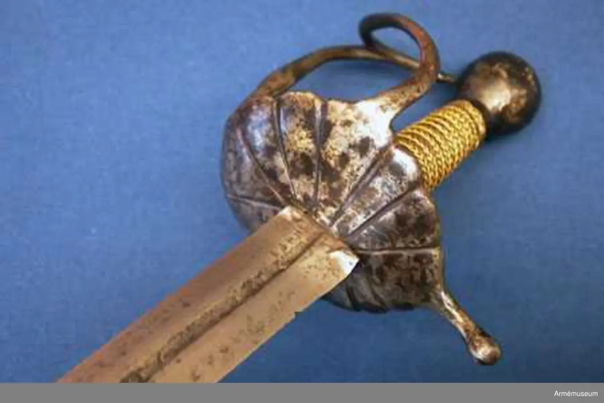 Klingan märkt med P-stämpel och "(CO)". Bredd vid fästet: 34 mm.

Fästet med upp-/nedvänd, äggformig knapp m icke ursprunglig låg nitknapp. Kavellindning av snodda mässingstrådar i reglementsenligt mönster är av senare datum. Randad, flat, svärtad parerplåt; något mindre på insidan än på utsidan. Dess kant är svagt runduddad och den undre sidan har en ornering i form av radialt ordnade ränder. "Nr: 191" inputsat. Handbygeln m förtjockning på mitten är intappad i knappen. Från parerplåten utgår en svängd, yttre sidobygel och ansluter till handbygelns övre del. Parerstången nästan rakt utstående m ett droppformigt avslut. Från parerplåtens insida utgår vertikal tumbygel. 

Klingan tveeggad m flat ås och hålslipning på bägge sidor. I dessa äro inslagna otydliga bokstäver "(CO)" och P-stämpel.