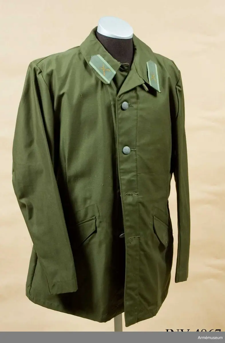 Storlek: C 52. Vapenrock m/1959, Svea livgarde. Tillverkad av olivgrönt  bomullstyg, enradig, högknäppt i halsen, har grensleif, två snedställda sidfickor och två bakfickor.
Kragspeglarna är försedda med truppslagstecken i grön textil.
UNIA 1977 6:101-112.