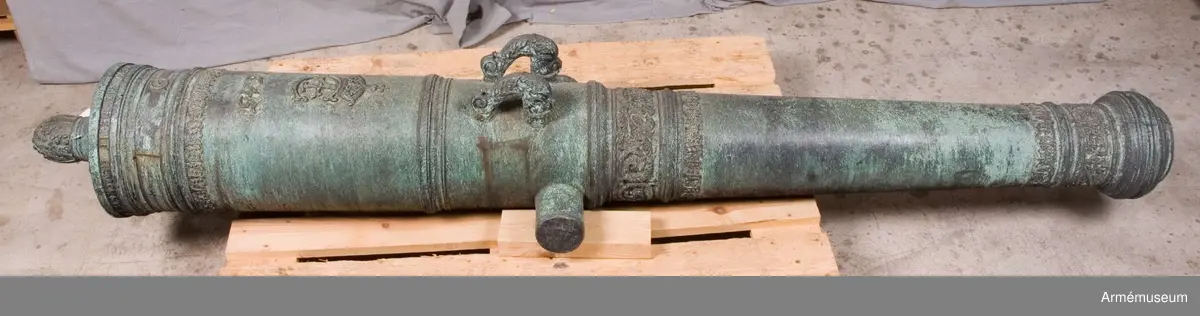 Grupp AI.
Med Kristian IV:s namnchiffer och därunder gjutåret 1645; å kammarbandet inskriften: FRANCISCUS. ROEN. ME. FECIT. GLYCKSTADT (Frans Roen gjorde mig i  Glückstadt). Loppets relativa längd: 21 kal. Kaliber: 9,8 cm. Vänster tapp märkt "8", kammarstycket "1646".