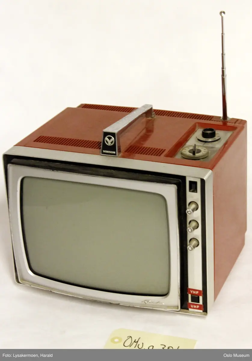 Rektangulær portabel TV med håndtak på toppen, antenne til dra ut bak til høyre og to hjul for frekvens, VHF og UHF på toppen. hull til ledning bak (som mangler). Tre små skruknapper foran for innstilling av lysstyrke, og lyd (ant., samt en av og på knapp for VHF/UHF.