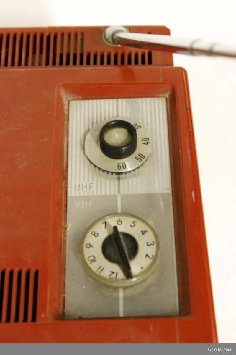 Rektangulær portabel TV med håndtak på toppen, antenne til dra ut bak til høyre og to hjul for frekvens, VHF og UHF på toppen. hull til ledning bak (som mangler). Tre små skruknapper foran for innstilling av lysstyrke, og lyd (ant., samt en av og på knapp for VHF/UHF.