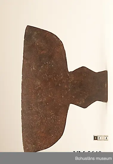 Handsmidd enkeleggad bred yxa med romboid holk med rektanguulärt uttag för skaft. Yxskaft saknas.
Viss gravrost.
Förvärvad 1952 från Johannes Olsson, Stillingön, Orust och då med uppgiften att yxan använts som bödelsyxa.

Svårbedömd tillverkningstid.

Ur handskrivna katalogen 1957-1958:
Bödelsyxa
L. 36,5. Br 24,5. Föremålet helt. Något rostat.