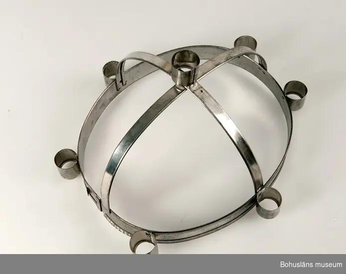 Luciakronan ställbar med oval nederdel med sex nitade ljushållare, från nederdelen utgår två tvärgående band i bågform. Där banden möts finns en sjunde fastlödd ljushållare.