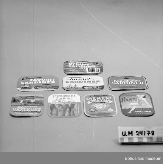 Åtta etiketter med olika motiv till Fiskebrödernas sardinburkar för inläggningar med sardiner i tomatsås. 
Etiketterna är tillverkade under olika decennier. Några med text på engelska respektive finska.