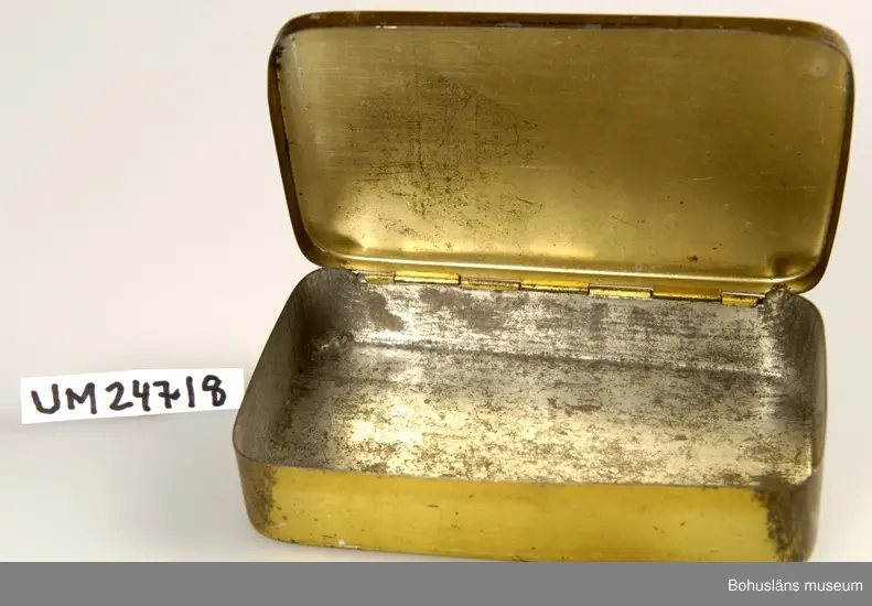 Föremålet visas i basutställningen Kustland,  Bohusläns museum, Uddevalla.
471 Tillverkningstid 1940-TAL ?

Locket sitter fast i ena långsidan. På locket finns det bild på en tiger och text: "TIGER BRAND NO 512 A.-B. SVENSKA TOBAKSMONOPOLET".
Asken är tom.
När asken kom till museet låg det små svenska flaggor inuti. 
Se UM24719.