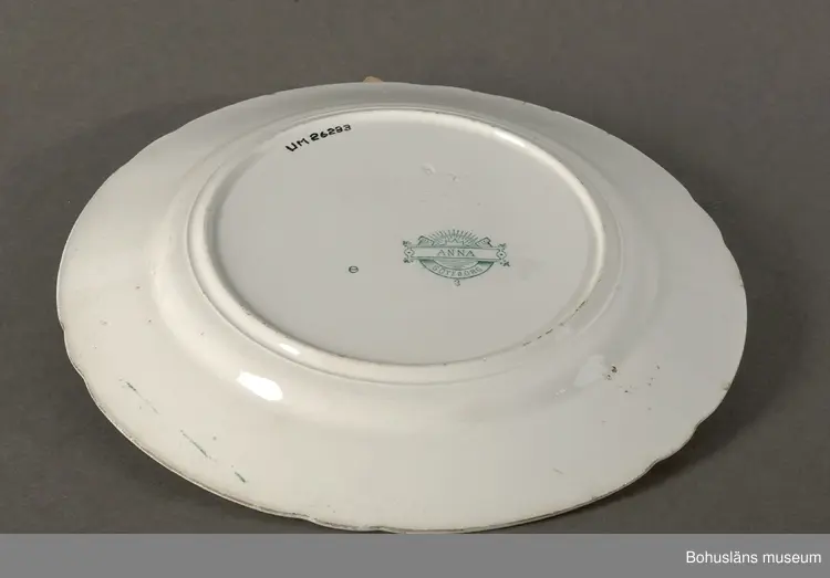 Tallrik modell "Anna". 
Stämplad med en stämpel som användes mellan åren 1902-1904. 
I priskurant från 1902 avbildas servisen med detta mönster, men omnämns endast som "tryckt dekor".
I priskurant från 1915 finns den med på färgplansch under namnet "Grön Anna".
Ägaren eller en man med anknytning till Göteborgs Porslinsfabrik lär ha kommit från Svarteborgs socken, Bohuslän. Han var god vän med fröken Anna Axelsson (1904-1985), Rom Östergården 1:12, Dingle, Svarteborg socken. Anna arbetade en stor del av sitt liv på Dingle mejeri. Efter henne lär servisen ha kallats "Anna". Uppgiften kommer från personer i Svarteborgs hembygdsförening i början av 1990-talet, vilka tidigare fått del av denna berättelse.
(Om ovanstående stämmer bör Anna ha varit nyfödd flicka när namnet på servisen bestämdes.)
År 1916 köpte Rörstrand Göteborgs Porslinsfabrik och flyttade 1923 all sin produktion dit. I köpet ingick även en rad modeller bl.a. denna servis som Rörstrand fortsatte produktionen av. Dekoren återupptogs på 1960-talet, men på servisgods av helt annan formgivning. Mönstrets namn ändrades då från "Anna" till "Grön Anna".
Mönstret har en ren nyrokokoformgivning. Det har i mindre omfattning även producerats i en lila färg. Mönstren "Anna" och "Grön Anna" har haft stora försäljningsframgångar och en av Göteborgs och Rörstrands långkörare.

Litteratur:
Göteborgs porslinsfabrik. Priskurant 1920.
Priskurant öfver Göteborgs porslinsfabriks tillverkningar 1920.
Artikel i Antik & Auktion nr 1 1983. Göteborgs porslinsfabrik - den okända fabriken där Grön Anna föddes. Skriven av Jane Fredlund.