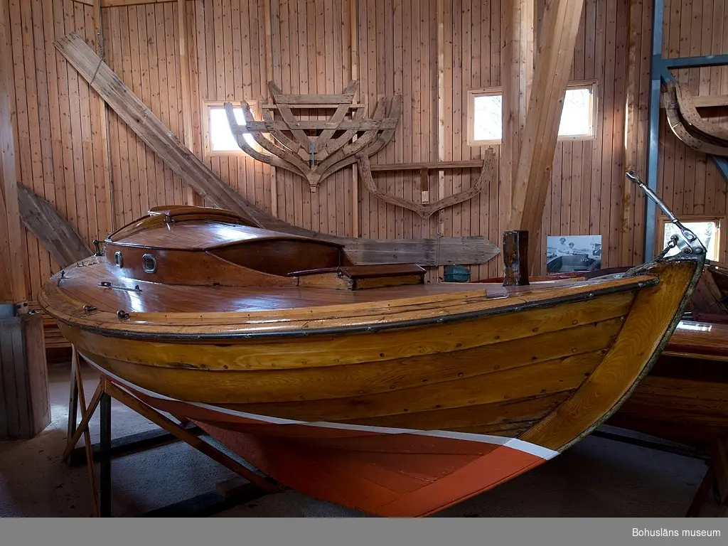 Spetsgattad. Klinkbyggd. Bord och spant av ek. Borden är nitade.
Däck av oregonpine. Ruff av mahogny och oregonepine (taket). Masten (H 10,3 m) och bommen (L 3,1 m) är gjorda av oregonpine.
Tidigare var båten gaffelriggad men i samband med en ombyggnad 1952 fick hon däck, ruff och en ny modern rigg samt kryssfock och storsegel av bomull tillverkat av Hasses segelmakeri i Göteborg, se UM026494 - UM026495. Se Länkade filer under Tilläggsinformation.
På sittbrunnens sarg sitter en namnskylt i trä; "NYMF".
Ett blått kapell, sprayhood, med två vita stänger från 1980-tal samt en båtshake förvaras i ruffen. Se Länkade filer under Tilläggsinformation.

Båten ägdes på 1930-talet av Karl Otto Jonasson. År 1941 sålde han den till Folke Gunnarsson och Rune Olsson. Fem år senare köpte Folke ut Rune.
Folke var med i Segelsällskapet FRAM i Göteborg. Båten kallades Nymf och hade nr 64 i segelsällskapet FRAM. År 1988 tog Karl-Erik Karlsson över båten.

Enligt Sveriges befolkning 1900 heter båtbyggaren Karl Alfred Fredriksson Stjërn, född i Kville 1857.
 
Litteratur: 
Börjesson, E, Börjesson, L., Dunér, m fl.: Kostern. Segelsällskapet Fram 100 år. 1896-1996. Göteborg 1996.
Sörenson, Reiners: Stjerns båtbyggeri på Galtö. Ur Träbiten nr. 93, Föreningen Allmogebåtar, Göteborg 1996.
Hasslöf, Olof: Svenska Västkustfiskarna, Stockholm 1949, sidan 296 ff,
Fredriksen, Christine: EBBA och NYMF - nöjesbåtar vid Bohuskusten. BOHUSLÄN. Årsbok 1999. Handel och hantverk. Bohusläns Hembygdsförbund och Bohusläns museum, s. 87-104.

Se Bilagepärmen UM26491: Träbiten nr 93 samt information från Segelsällskapet FRAM.
Gaffel och äldre bomullssegel finns el. uppgift från givaren kvar.
Uppgifterna kompletterade 2002-09-06/A-LS

Se Bildarkivet UMFA55001:1, familjebild från 1934 samt UM031358, prispokal från 1935.