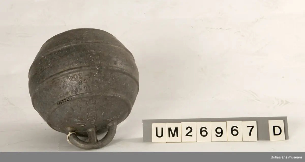 Fem klotformade flöten av metall (aluminium eller zink?). Beskrivningar av flötena i storleksordning följer här:
1. Omkrets 64 cm, med tre upphöjda ränder runtom på mitten och korta upphöjda ränder på tvären mellan dem på några ställen. I utstickande rektangulär del med rundade hörn finns två runda hål bredvid varandra. Text i relief: MANUFACTURERS PHILIPS ...(Oläsligt) TRAWL PRODUCTS GRIMSBY? ENGLAND ? (Svårlästa ord). Oläslig text p g a att den är bortsliten även på ytterligare ett ställe. Slitet.
2. Omkrets 63,5 cm, med sju upphöjda ränder, den mittersta bredare än de övriga. Två rundade metallöglor med gemensam mittdel sticker ut. Text i relief: AUTRIEB ? (Svårläst)...(Oläsligt) Märke som ser ut som ett kantigt stort S och siffrorna 197. Mycket smutsigt, fläckvis vit beläggning.
3. Omkrets 63 cm, slät yta utan upphöjningar, målad i vitaktigt grönblått i två olika nyanser, färgen delvis avsliten. Utstickande del med två närmast fyrkantiga hål. Text i relief: ... (Oläsligt ord) DE ... (Oläsligt ord) PARIS. Stor rostfläck. Mycket slitet.
4. Omkrets 55,5 cm. Med fem upphöjda ränder runtom. Rundad del med två kvartcirkelformade hål sticker ut. Text i relief: MADE IN SPAIN LA CORONA, bild av en fyr med ljusstrålar samt patentnummer med 39 siffror i. Samma? text/bild/siffror finns på ytterligare ett ställe fast är där mer sliten. Slitet.
5. Omkrets 37 cm. En upphöjd rand på mitten, för övrigt slät yta. En ögla sticker ut på ett ställe. Knutet runt den finns rester av snöre. Slitet. Rostfläckar m fl fläckar.

För uppgifter om brukaren se UM026962
Se även Bohusläns museums arkiv, arkivnummer 389.