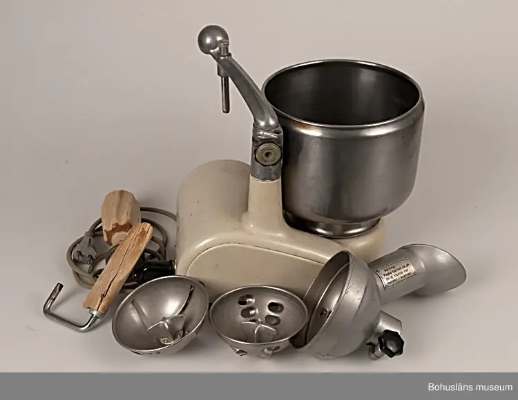 Hushållsassistent från 1940-talet av märket Electrolux.
Stomme med elmotor av ursprungligen beigemålat gjutjärn med löstagbar arm, armfäste och övre stativ av aluminium. Dämpande gummiknoppar undertill och på ena sidan. Rostfri, löstagbar skål. Elsladd av grått gummi med kontakter av bakelit.
Tillhörande redskap i metall och björk; blandare, degrulle av trä, rivjärnssats och skrapa av trä. Givaren kommer att komplettera med grönsakskvarn, köttkvarn, korvhorn. 

Efter många års flitig användning var färgen på maskinen väldigt sliten varför den målades om. På sidan har texten ELECTROLUX funnits.