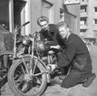 Två unga män undersöker en motorcykel utanför Nils Svenssons Cykel och Motor