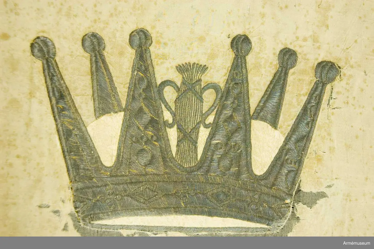 Duken vit med i guld broderat anglosachsiskt O under furstlig krona. På tillhörande lapp av äldre modell anges att Visby stads beväringsbataljon erhöll fanan 1832.