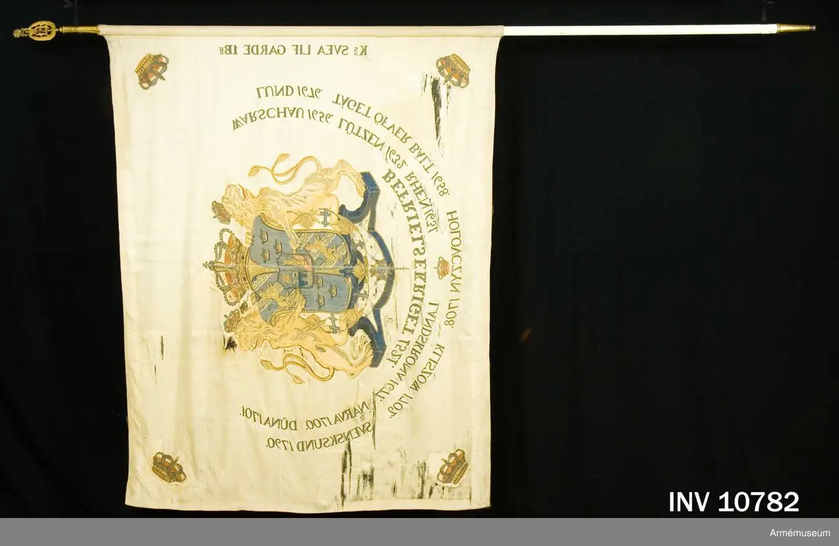 Duk av vit sidenkypert varå broderat lika å båda sidor, riksvapnet omgivet av segernamnen, slutna kronor i hörnen. Kravatt med guldfrans tillhör. Fanstången är vitmålad. Spets med Oskar II:s namnchiffer.