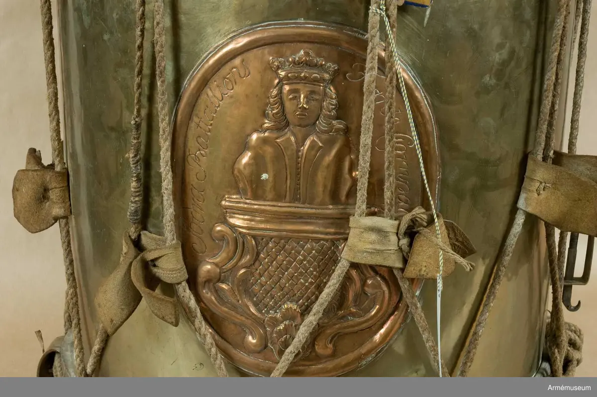 Grupp B III.
Gjord av mässingsplåt med grönmålade träramar. Snörad. Snarrsträngar har funnits, men saknas nu. Vingskruven, med hållare, för dessas spännande finns dock kvar. På hållaren är ingraverat: "Skänkt af P. (J) G. Bergman, Fendrich vid Borg.skapets Södra Bataile 5:te Comp. den 3 April 1764". Har en påsatt, oval kopparplåt med S:t Eriks bild, därikring är ingraverat: "Södra Batallions Femte Compagnie". Bärrem av brunt läder. Gåva från Borgerskapets militärkorpser. Tillhört Stockholms borgerskaps infanterikår./Mars 1939 A Lilliehöök. 