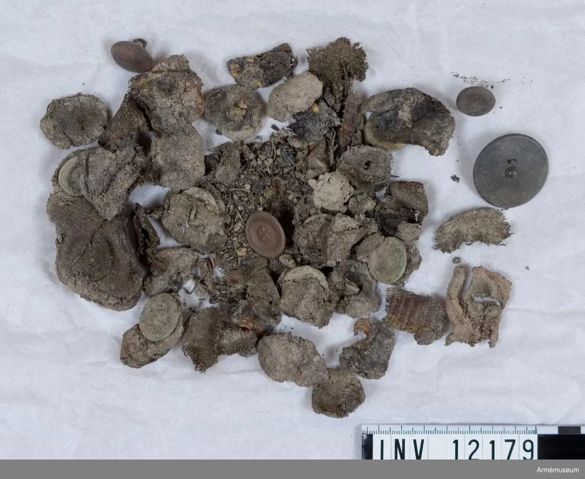 Grupp C I.
Dräktfragment med knappar. Jordfynd 1959, Blidö Furusund Tullåkern.