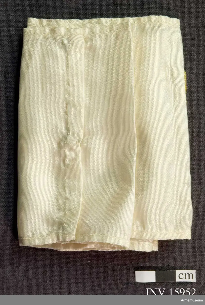 Grupp C I.
Armbindel - 10 cm bred av vitt sidentyg med påsytt  skyddskårsemblem broderad av silke, som består av två delar (blått och gult). Omkring emblemets kant och i mitten bokstaven  "S" (första bokstav i ordet skyddskår - suoluskunta på finska), broderad av ljusgrått silke. Ovanför bokstaven "S" tre små grankvistar broderad av brunt och grönt silke.