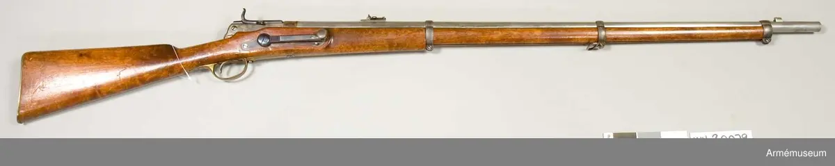 Grupp E II. 
Antal refflor: 6 st. Reffelstigning: Ett varv på 112,8 cm.

Pipan är blank och ursprungligen avsedd för ett kammarladdningsgevär m/1864 (AM 4428). Korn och bajonettklack äro lika som på sistnämda modell. Vinkelklaffsaiktet sitter 10,7 cm framför lådans främre ände. Den långa siktarmen är utbildad till ett med löpare försett remsikte, vilket är försett med siktskåror, men saknar gardering. Baktill är pipan inskruvad i framänden på en gråhärdad låda, vilken framtill är rätt djupt. Lådans bakre parti är grundare och har i botten hål för avtryckaren. Från lådans bakre ände utgår ett 7,5 cm långt svansjärn, som längst fram på översidanångt hål genombruten klack.

Mekanismen har utvecklats ur Hagströms kammarladdningsmekanism (AM 4428). Slutstycket är 10 cm långt, samt har på översidan en längsgående ränna. Längst bak på översidan en längsgående ränna. Längst bak på undersidan har det ett par parallella klackar, vilka genombrytas av ett hål och stå på ettavstånd av 1,3 cm från varandra. Dessa klackar placeras på var sin sida om den från svansenjärnets översida utgående klacken. Genom hålet i slutstyckets klackar och genom hålet i svansjärnets klack går en skruv, kring vilken slutstycket är rörligt. Litet bakom framänden går från slutstyckets undersida en kraftig klack nedåt samt litet bakåt. En annan, tunnare sådan klack går parallellt med den förstnämda omkring 1,3 cm längre bak. På högra sidan äro bägge klackarna avfilade omkring 3 mm, men den bakre klacken har  längst ned en utstående, 5 mm hög tand. I slutstyckets övre högra kant går ett 0,65 cm brett spår in till slutstyckets urborrning. Framtill börjar spåret 1,1 cm bakom slutstyckets framkant, men baktill går det ända ut i kanten. På framplanet har slutstycket ett 5 mm långt, med tätring av stål försett munstycke, vars yttre diameter är 14,5 mm. I slutstyckets urborrning är spiralfjäderlåset anbringat. Urborrningen tilltäppes baktill av en bakifrån införd, 2,8 cm lång järnpropp, vilken framtill har en 1,1 cm djup urborrning för den kring nålskaftet lindade spiralfjäderns bakre ände. Från proppens högra sida går en skena snett uppåt, vilken är inpassad i och utfyller spåret i slutstyckets övre, högra kant. Proppen fasthålles av en genom lådans högra vägg gående skruv. Tändnålen, vars fria del är 2,5 cm lång, är baktill och det av mässing tillverkade nålskaftet är framtill inpassat i resp. bak- och framänden av en 3,3 cm lång, med hel- och halvspännshak försedd järncylinder, vilken passar i och kan glida i slutstyckets urborrning. Baktill är denna cylinder urborrad till ett djup av 2,7 cm, i vilken urborrning spiralfjäderns främre ände anbringats. Från cylinderns högra sida går en klack, vilken är lika lång som sylindern, snett uppåt åt höger och är inpassad  i spåret på slutstyckets övre, högra kant. En 8,5 cm lång skena,  som ligger längs utsidan av slutstyckets övre högra kant, är  gjord i ett stycke med sistnämda klack. En 1,2 cm lång,  horisontalt ställd tapp utgår från skenan 3,1 cm bakom framänden och omkring 2 cm framför bakänden finnes ett framtill krusat tumgrepp. Nålen går ut genom ett hål i munstyckets centrum. Nålrörets bakre mynning omgives av en läderpackning. Litet framför slutstyckets bakre klackar sticker stångens bakände ut genom slutstyckets undersida. Stångfjädern är med en skruv fäst vid slutstyckets undersida framför stången och trycker den sistnämda uppåt. Avtryckarens övre, kloliknande del ligger an emot stångändens översida och pressar vid avfyrning stångänden nedåt. På stockens högra sida är ett låsblecksliknande beslag fastgjort med tre skruvar. Framtill har detta beslag tre "hävarmstappar".