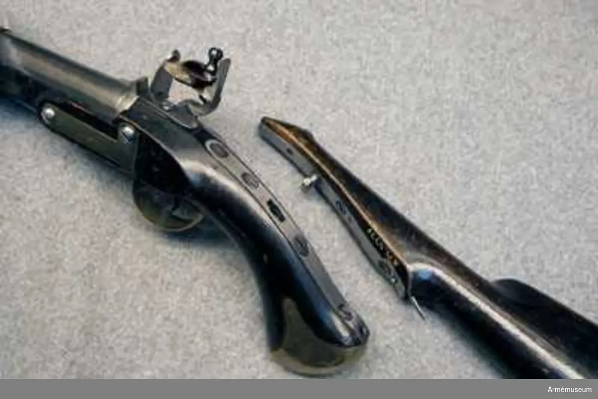 Pistol med flintlås.
Studsarpistol m/1807 (1806?) av Helvigs konstruktion. Längd med påsatt löskolv: 712 mm. Pipan är rund. Svansskruven har baktill en hake, som är inpassad i ett hål i det vid stocken fästa svansjärnet. Ett högt, båtformigt mässingskorn sitter 4,2 cm bakom mynningen. På svansjärnet sitter ett högt ståndsikte. Svansjärnet fasthålls av en uppifrån isatt korsskruv. På pipans översida krönt N T (Norrtälje), på undersidan ett P och på vänstra platten en otydlig stämpel. På svansjärnet en otydlig kronstämpel. Loppet har 4 spiralräfflor.

Låset har platt bleck, fängpannearm och eldskärm. Studeln har en egendomlig, kantig form. Slag och eldstålsfjädrarna är så krökta att främre låsskruven går inom deras bukter. pannskruven går inifrån, men skruven för eldstålsfjädern utifrån. På bleckets utsida under eldstålsfjädern ett S, på insidan siffran 2 och en otydlig kronstämpel.

Stocken är av björk och svart, till vänster om varbygeln främre arm en otydlig stockmakarestämpel och till höger om denna arm spår av rött lacksigill. Ovanför sidblecket är inslaget numret 16. Beslagen är av mässing. Kolvkappan har rätt korta, avrundade flikar och är hoptryckt från sidorna. Den fasthålls av en skruv i centrum. Varbygelns bakre arm går ned till kolvkappan och är fäst med en skruv. Den korta främre varbygelsarmen har docka. Sidblecket är platt och böjt i rät vinkel. Pipan fasthålls av två band, vilka kvarhålls av stift. Näsbandet är upptill utskuret för kornet och har nedtill en kort, bakåtgående spets. Det andra bandet har nedtill en kort framåtriktad spets. På sidblecket, näsbandet och kolvkappan inslaget G S. På varbygelns bakre arm en stämpel med ett monogram av A.L.

I kolvens övre sida är ett kraftigt "anslagsjärn" infällt och till ungefär 1 cm från svansjärnets bakände. fasthålls av fyra skruvar. Anslagsjärnet går från kolvkappan till ungefär 1 cm från svansjärnets bakände. Längst ned vid kappan finns i järnet ett runt hål och omkring 8 cm längre upp har det ett avlångt hål.

Löskolven är svart, av björk och har bakplåt av mässing. Löskolvens "hals" är avsneddad på undersidan så att den där noga passar till pistolkolves översída. I detta avsneddade parti är "häftjärnet" infällt och fasthålls av tre skruvar. En bit nedanför häftjärnets överkant sitter "häfttappen". Denna består närmast häftjärnet av en omkring 6 mm hög, cylindrisk tapp med 7 mm diameter. På denna tapp sitter ett rektangulärt, 13 mm långt, 5 mm brett och 5 mm högt ax på tvären med häftjärnet längdriktning. På insidan av häftjärnets är en lång "häftfjäder" placerad. Häftfjädern sticker nedtill ut omkfing 1,7 cm nedanför häftjärnets bakände. Litet ovanför denna bakände genombryts häftjärnet av ett hål, genom vilket en på häftfjädern sittande tapp utsticker.

När man påsätter löskolven, inpassar man häfttappen i anslagsjärnets övre hål, vrider löskolven åt vänster och trycker in häftfjäderns utstående del. Då anslagsjärnet och häftjärnet ligger på varandra, släpper man häftfjädern, varvid häftfjäderns tapp drivs ned i anslagsjärnets runda hål samt sålunda fastlåser löskolven vid pistolen. Därigenom kunde man skjuta med pistolen stödd mot axeln alldeles som med ett gevär. Ett par pistoler av denna modell består av en studsarepistol, lika den som ovan beskrivits, och en slätborrad blänkare- eller flankörpistol (se AM 4780). Till varje pistolpar hördes en löskolv, också kallad "löst anslag", och en lös laddstock. Löskolven och laddstocken passade till bägge pistolerna.