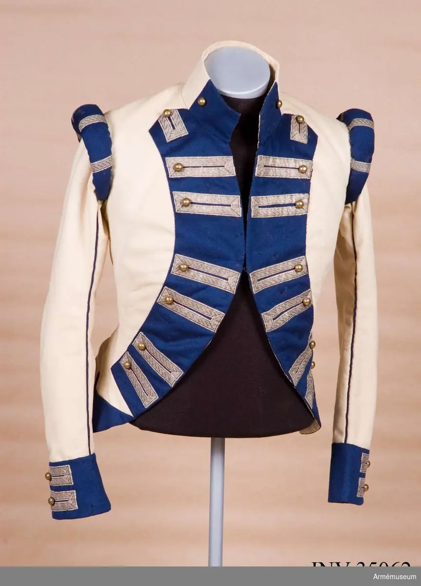 Rekonstruktion av jacka m/1781 för officer vid Lätta livdragonerna.
Jackan är sydd av vitt kläde med kragspeglar, bröstrevärer, axelkarmar och ärmuppvik i mörkblått kläde. Passpoaler av blått kläde i ryggsömmar och främre delsömmar på ärmarna.
Den är dekorerad med metallgaloner på bröstrevärer, axelkarmar och ärmuppslag, och har 16 icke funktionella kulknappar av mässing fram, samt 2 i varje ärmslut och 2 vid ryggslutet bak.
Mitt-fram-linjen är kraftigt svängd, och framstyckena är vadderade över bröstet. Jackan stängs mitt fram samt i ärmsprunden med hysk och hake. 
Den är konstruerad med avskärning i midjan, samt insnitt fram. Separata sidstycken. Skört utan slits bak.
Axelkarmarna är vadderade och står rakt upp.
Jackan är helfodrad med vitt bomullstyg.

Plaggets skärning och sömmar, de vadderade axeltungorna, de djupt skurna bröstrevärerna, uppviken, fodret m.m. indikerar ganska tydligt att den är tillverkad senare, troligen under sent 1800-tal. Även tygkvalitéerna indikerar en yngre datering.