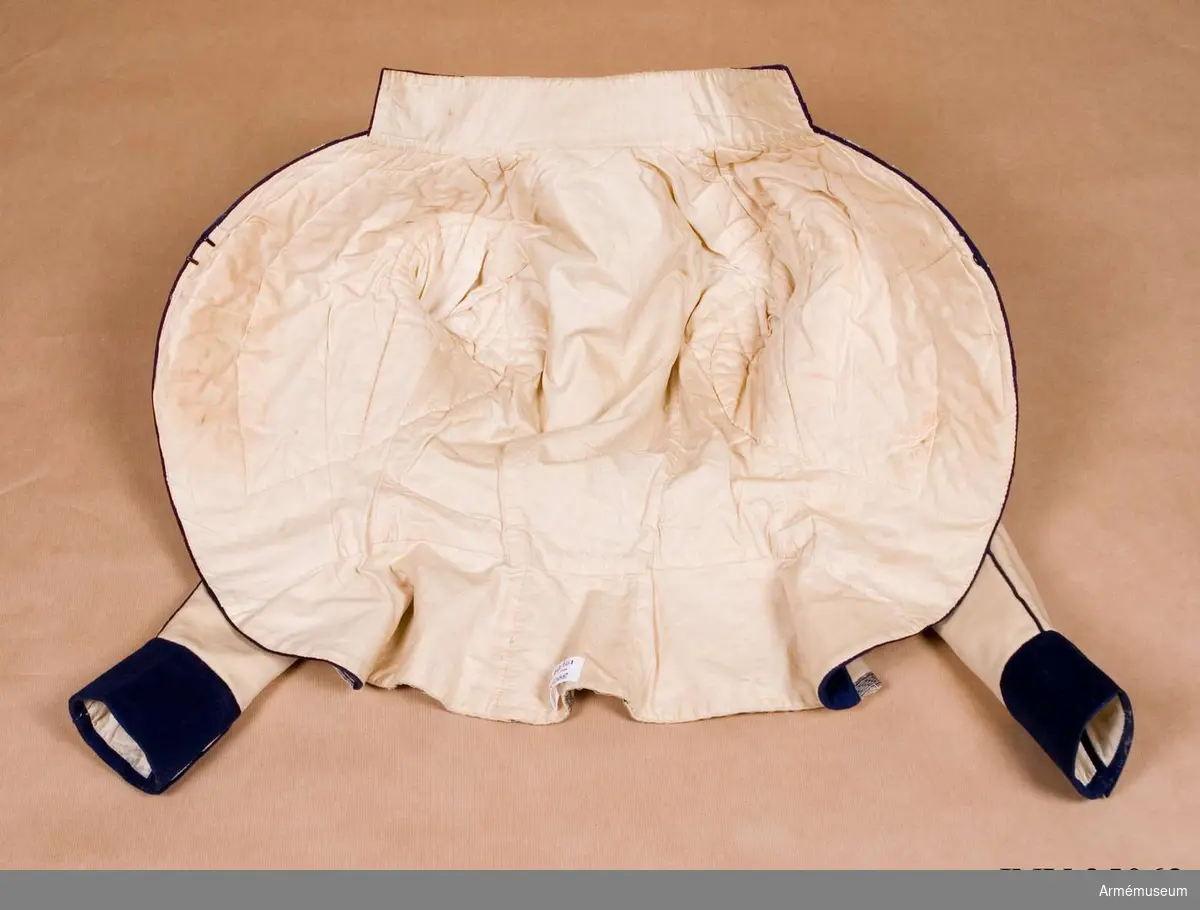 Rekonstruktion av jacka m/1781 för officer vid Lätta livdragonerna.
Jackan är sydd av vitt kläde med kragspeglar, bröstrevärer, axelkarmar och ärmuppvik i mörkblått kläde. Passpoaler av blått kläde i ryggsömmar och främre delsömmar på ärmarna.
Den är dekorerad med metallgaloner på bröstrevärer, axelkarmar och ärmuppslag, och har 16 icke funktionella kulknappar av mässing fram, samt 2 i varje ärmslut och 2 vid ryggslutet bak.
Mitt-fram-linjen är kraftigt svängd, och framstyckena är vadderade över bröstet. Jackan stängs mitt fram samt i ärmsprunden med hysk och hake. 
Den är konstruerad med avskärning i midjan, samt insnitt fram. Separata sidstycken. Skört utan slits bak.
Axelkarmarna är vadderade och står rakt upp.
Jackan är helfodrad med vitt bomullstyg.

Plaggets skärning och sömmar, de vadderade axeltungorna, de djupt skurna bröstrevärerna, uppviken, fodret m.m. indikerar ganska tydligt att den är tillverkad senare, troligen under sent 1800-tal. Även tygkvalitéerna indikerar en yngre datering.