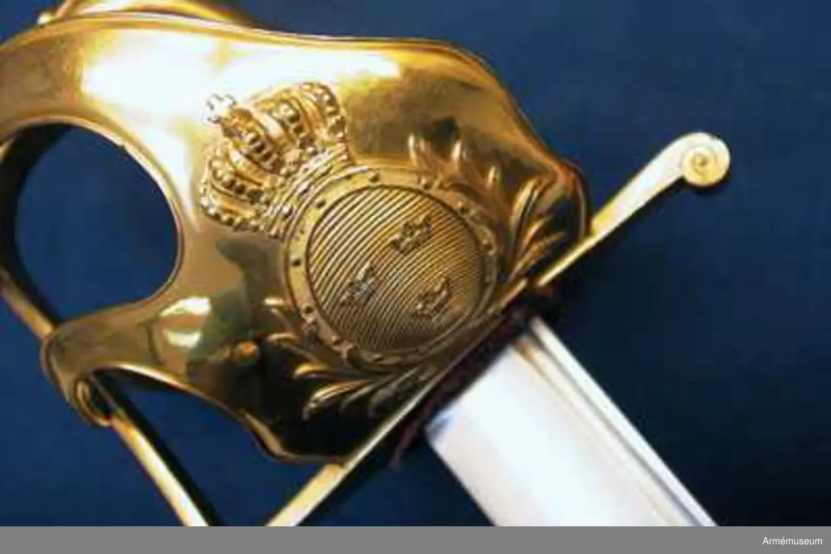 Klingbredd upptill 33 mm. Klingan är krökt och eneggad. Längs ryggen har den en blodrand och framför den en grund skålslipning. Blodranden slutar ungefär 28 cm ovanför udden till blodrandens slut är klingan slipad med egg även å ryggsidan. Fästet är av förgylld mässing. Kaveln är klädd med svärtat fiskskinn, och kring den går en spiralräffla 15 varv. Kaveln har baktill ryggbeslag, som upptill övergår i en låg kappa, vilken pryds med kraftigt ciselerat ornament i form av en stiliserad lagerkrans, vilken omger den lilla fasonerade nitknappen. Parerstången är rak samt har fyrsidigt tvärsnitt. Baktill avslutas den av en nedböjd knapp, vars kanter är ornerade med ciselerade spiraler. På parerstångens övre sida är siffran 3 inslagen. Från parerstångens främre ände utgår handbygeln i rät vinkel. Handbygeln har fyrsidigt tvärsnitt blir bredast framför kappans främre kant. På yttersidan finns en stor uppböjd parerplåt, på vilken finns en krönt oval sköld med tre kronor. Skölden omgives av stiliserade palm- eller lagerkvistar, allt i sicilerat arbete. Från parerplåtens övre spets går en spång, som är böjd i S-form. till handbygeln, som den träffar vid dess övre krök. På andra sidan om föreningspunkten förlängs spången av en liten avrundad utåtböjd flik. En annan liknande spång går fråm parerplåtens främre kant till handbygelns mitt. På innersidan finns en liknande men mindre parerplåt, från vars spets en S-formig spång går till handbygeln, vilken den träffar mitt emellan de ställen, där de båda ytterspängerna förenas med denna bygel. Ryggbeslaget, kappan, handbygelns främre sida, parerplåtarna och alla spänger har längs kanterna en ingraverad rand. På innersidan finns en tumrem, vars ena ände fasthålls av 6 varv av den kring kaveln gående silvertråden och vars ände är instucken mellan kaveln och parerplåten samt är försedd med ett hål, genom vilket tången går.
