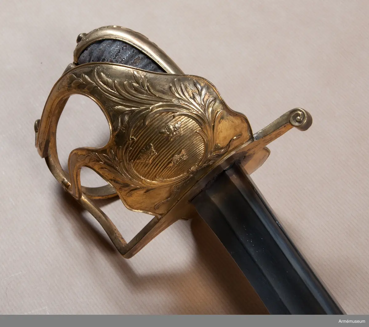 Sabeln är lik modellsabeln AM 36629, men avviker i frågan om fästets ornering. Den på kappan kring nitknappen anbringade ciselerade kransen är här större och går ned på ryggbeslaget och den på yttersidans parerplåt anbringade skölden med tre kronor är här större, ej krökt, nära nog cirkelrund och de sillerade palm- och lagerkvistar, som omger denna sköld, är här vida större och går in på ytterspängerna. Egendomligt nog finns såväl i Livrustkammaren som i ingenjör Orres samling sablar av denna typ, som på klingan har svenska riksvapnet med hessiska hjärtvapnet.