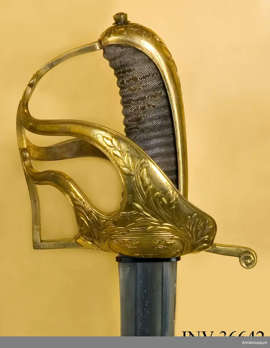 Sabeln är lik modellsabeln AM 36629, men avviker i frågan om fästets ornering. Den på kappan kring nitknappen anbringade ciselerade kransen är här större och går ned på ryggbeslaget och den på yttersidans parerplåt anbringade skölden med tre kronor är här större, ej krökt, nära nog cirkelrund och de sillerade palm- och lagerkvistar, som omger denna sköld, är här vida större och går in på ytterspängerna. Egendomligt nog finns såväl i Livrustkammaren som i ingenjör Orres samling sablar av denna typ, som på klingan har svenska riksvapnet med hessiska hjärtvapnet.