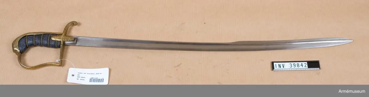 Grupp D II
Klingan är av samma typ som på infanteriofficerssabeln m/1859 och är svagt krökt. Upptill har den en längd av omkring 37 cm förstärkt avrundad rygg, men nedtill en bred, tveeggad klack. Den förstärkta ryggen fortsätter in på klacken, delar denna så att säga i två hälfter och slutar vid udden. Upptill på yttersidan finns svenska riksvapnet och "Nordstjärnan i sin strålglans", men nästan utslipat.Fästets beslag är av ursprungligen förgylld mässing. Kaveln är klädd med svärtat fiskskinn och kring den går fem refflor. I botten på dessa refflor är två mässingstrådar, bägge hopsnodda av två parter och båda snodda åt samma håll, anbringade. Baktill har kaveln ryggbeslag, som utom på mitten, är prytt med graverade, delvis ciselerade ornament och som upptill övergår i en kappa, vilken är ciselerad i formen av en maskaron. Parérstången är till större delen av sin längd rak, med rektangulärt tvärsnitt, men baktill är den starkt nedböjd och slutar i en närmast framåtböjd knapp. På sidorna är parérstången sparsamt graverad. Från parerstångens främre ände utgår handbygeln nära nog i rät vinkel. Handbygeln är nedtill insvängd, upptill utsvängd. Den har till större delen av sin längd rektangulärt tvärsnitt, och är på framsidan prydd med graverade ornament. Styrskenorna är ovala med avrundade ändar samt är prydda med graverade ornament.