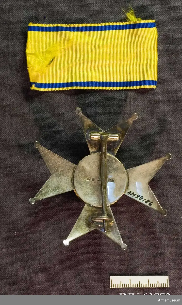 Grupp M II.
Kraschan tidigare buren av översten T.G.R Bergenstråhle. Ett johannitkors av silver med åtta uddar som var och en avslutas med en kula. Ljust mellanblå emaljerad glob med ornerad kant med nött förgyllning. Inom kanten ett stolpvis ställt omgivet av tre öppna kronor, ställda två och en - av guld eller förgyllt. På baksidan kontrollstämplar: "GFC", sk kattfot, "S", svårtydd stämpel samt "G 8".  Tillsammans med kraschanen ligger en bit band, 70 mm x 37 mm, gult med mörkblå kantränder.
