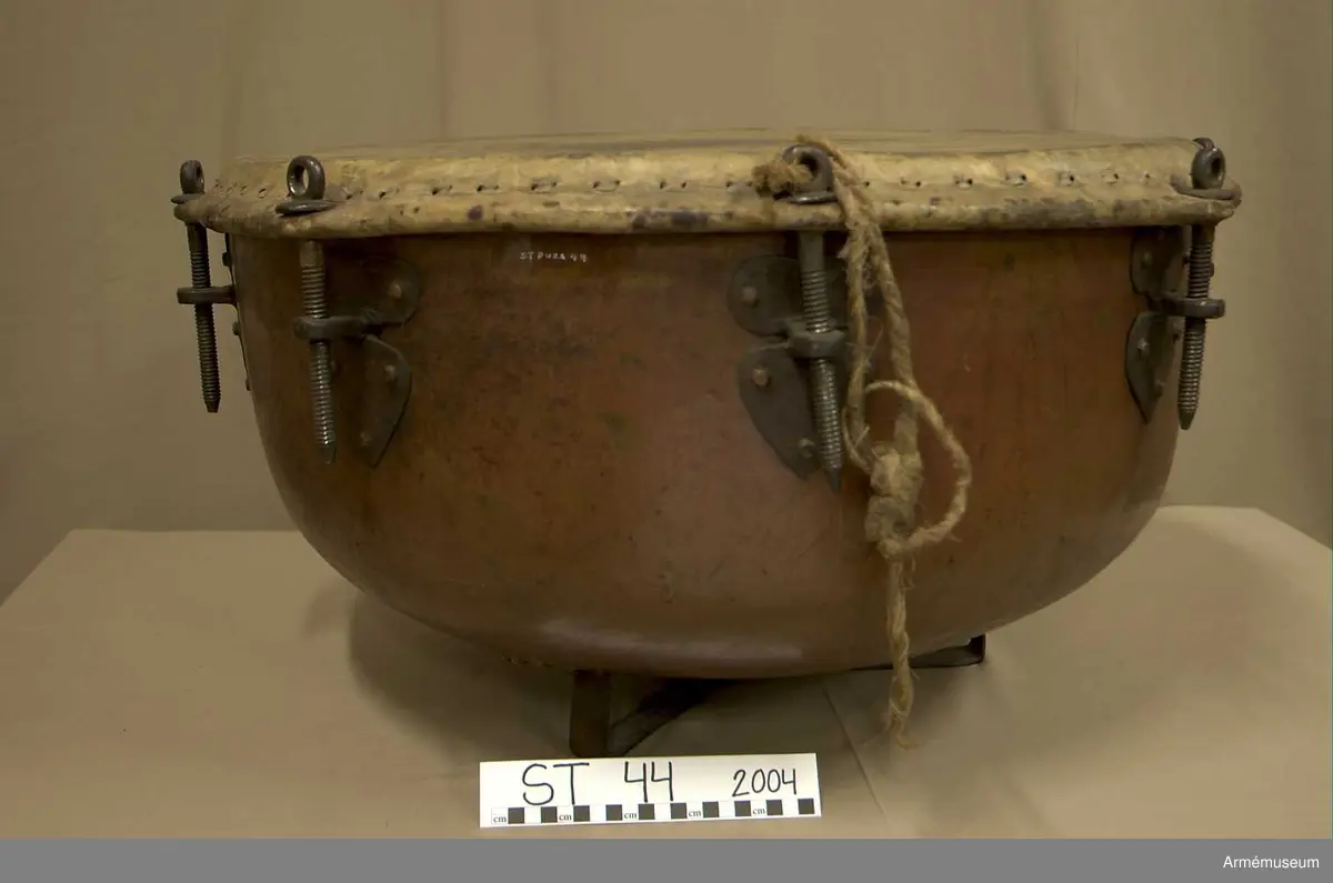 Grupp A.

Tillstånd 2005

Kittel:
Stor, vacker, orange och blank. Två prydliga lagningar där fot fäster i kittel.

Fot: 
Tredelad, stadig. Kan stå.

Spännskinn:
Ljust, fjälligt på mitten. Mycket. litet färgstänk. Efter spännringen fann jag två små trasigheter, annars intet.

Spännring:
Rostig. 

Spännskruv: 
Åtta stycken. Ett rep fastbundet i en av skruvarna.

Skruvfästen:
Åtta stycken. 

Bärrem:
Saknas.