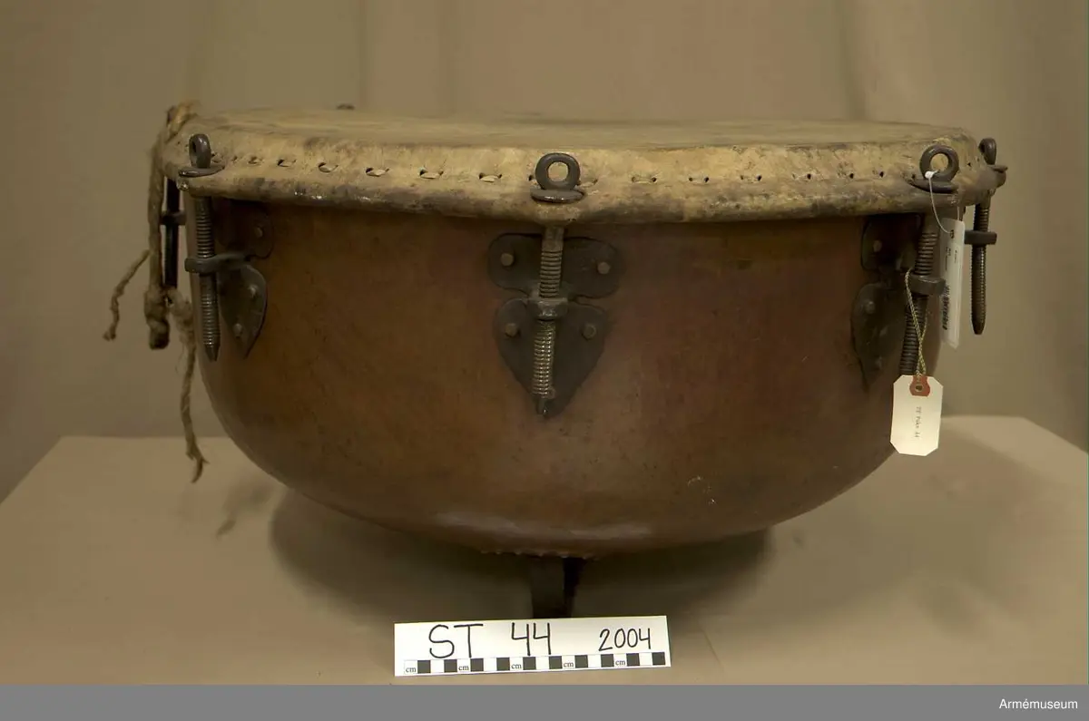 Grupp A.

Tillstånd 2005

Kittel:
Stor, vacker, orange och blank. Två prydliga lagningar där fot fäster i kittel.

Fot: 
Tredelad, stadig. Kan stå.

Spännskinn:
Ljust, fjälligt på mitten. Mycket. litet färgstänk. Efter spännringen fann jag två små trasigheter, annars intet.

Spännring:
Rostig. 

Spännskruv: 
Åtta stycken. Ett rep fastbundet i en av skruvarna.

Skruvfästen:
Åtta stycken. 

Bärrem:
Saknas.